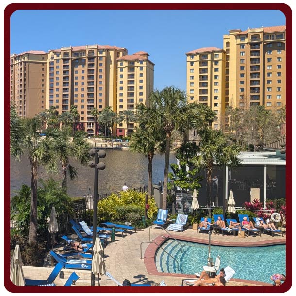 Image of Wyndham property with lake, palm trees, and a large building in the background. 
