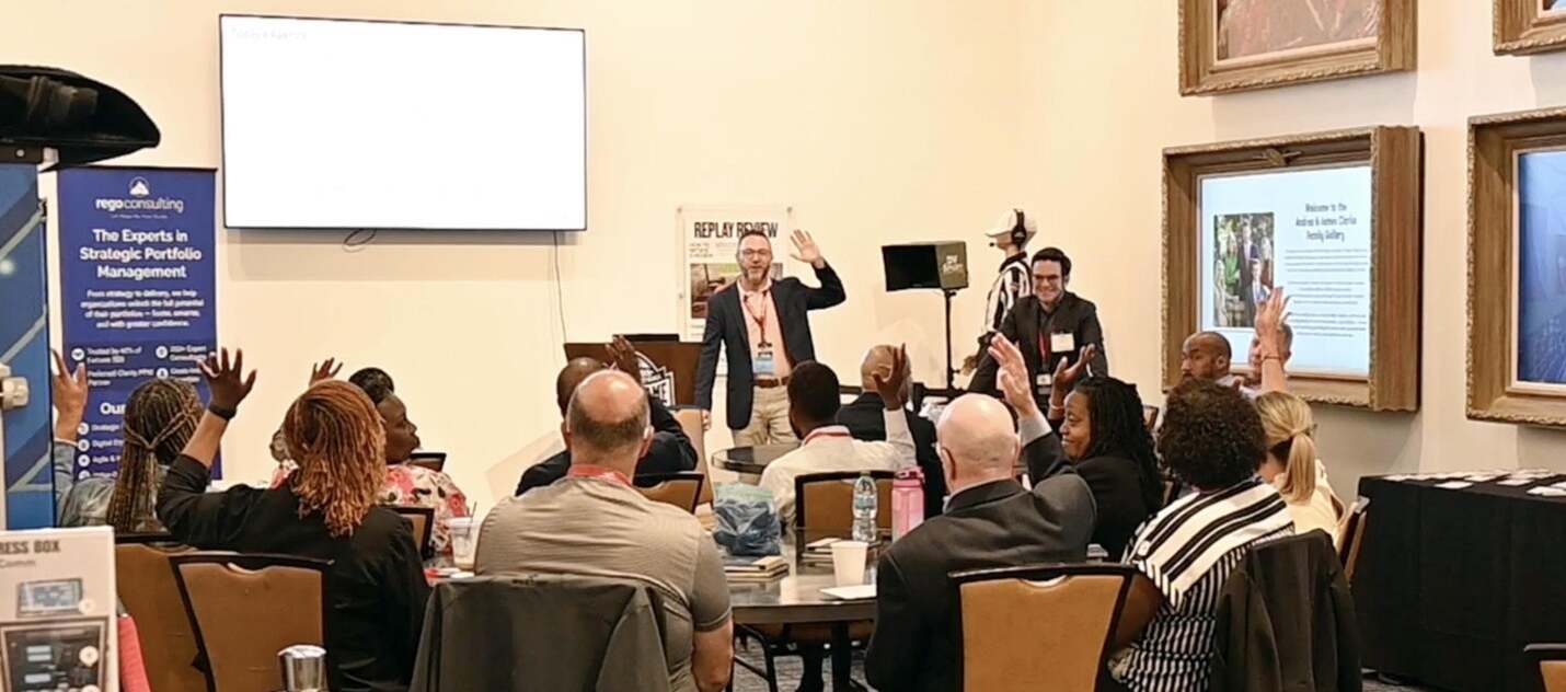 2025-05-Atlanta 3 Presenter engaging audience with raised hands during a Rego Consulting Clarity user group session.